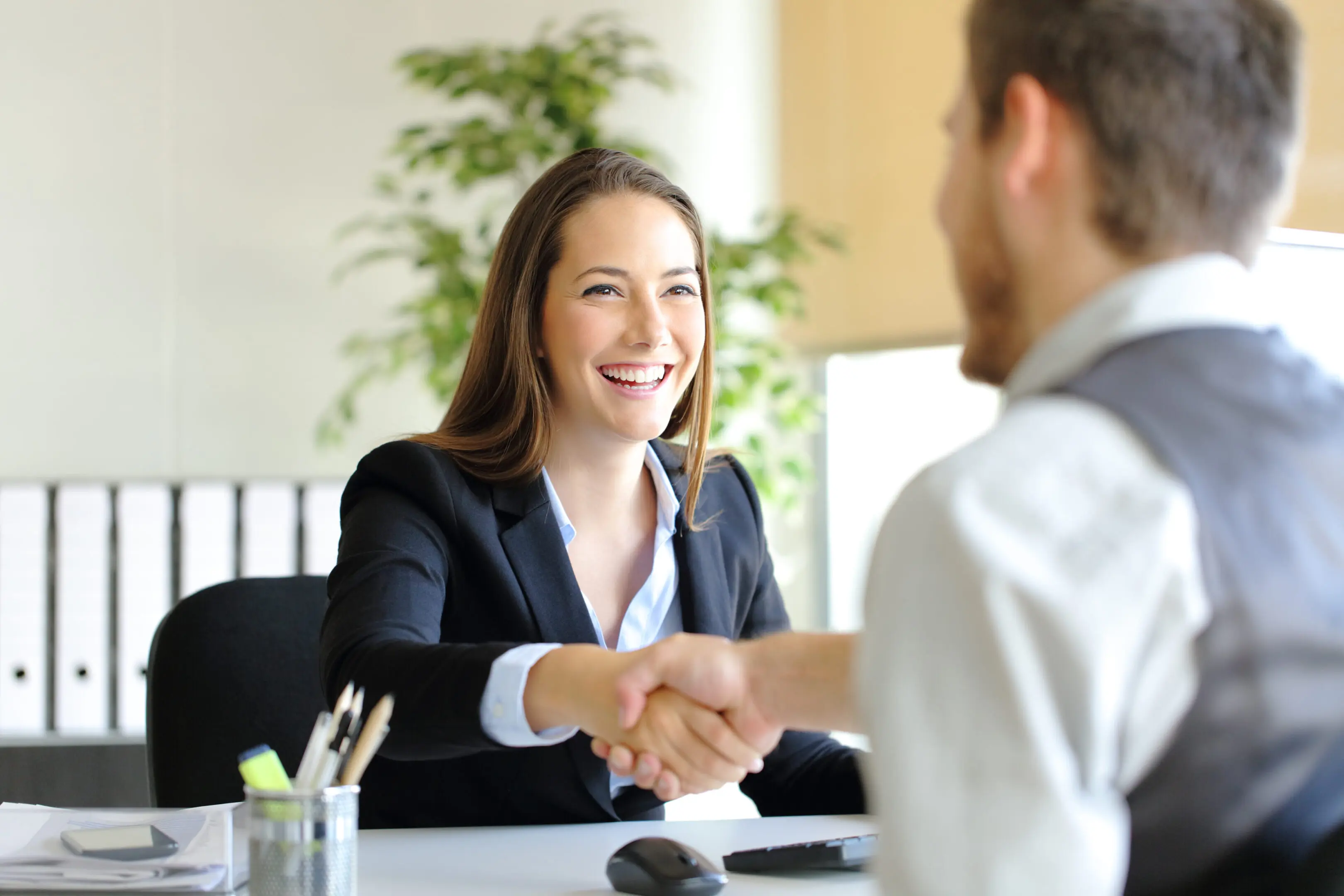 Business handshake between two smiling professionals.
