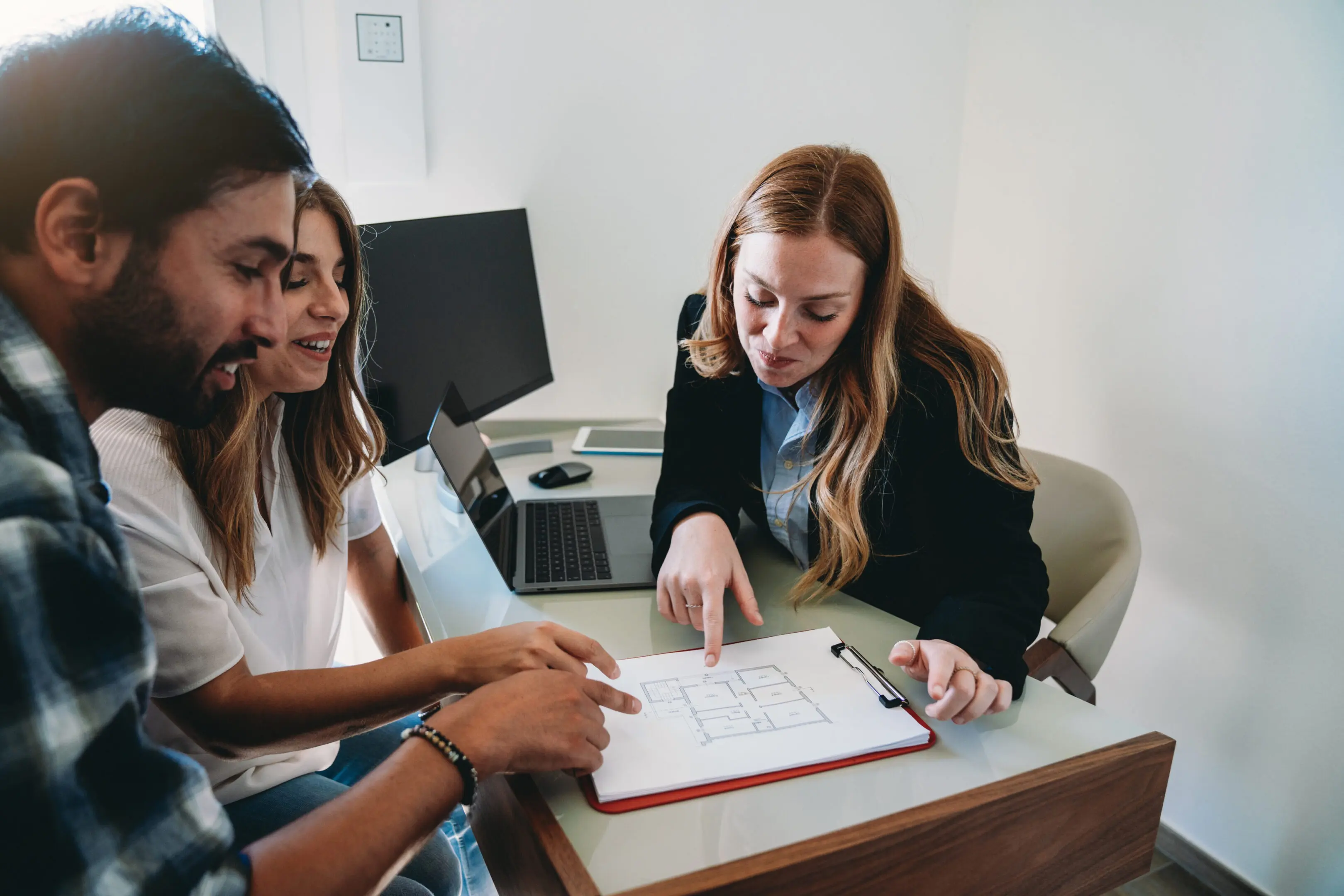 People discussing a blueprint at a desk.
