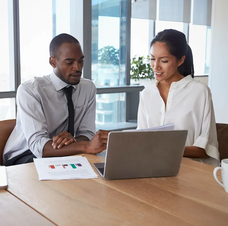 Two colleagues discussing work at a laptop.