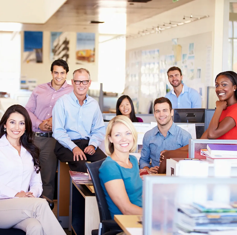 Smiling office team gathered at desks.